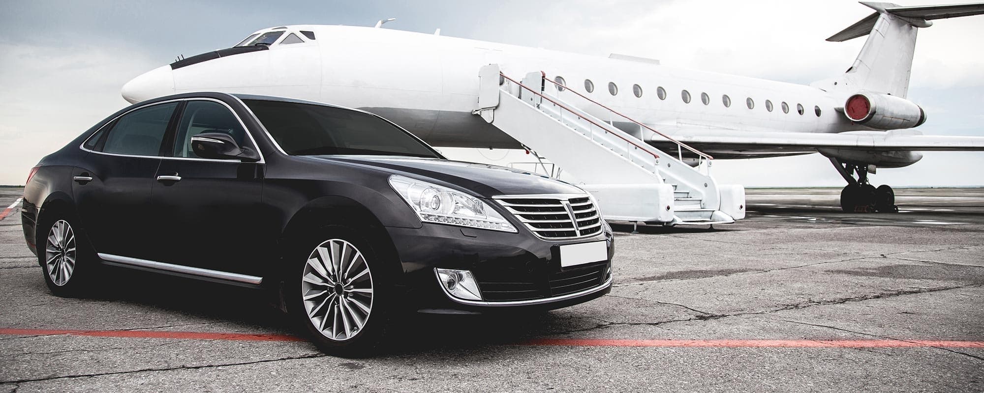 Black sedan waiting at private jet on airport ramp exterior