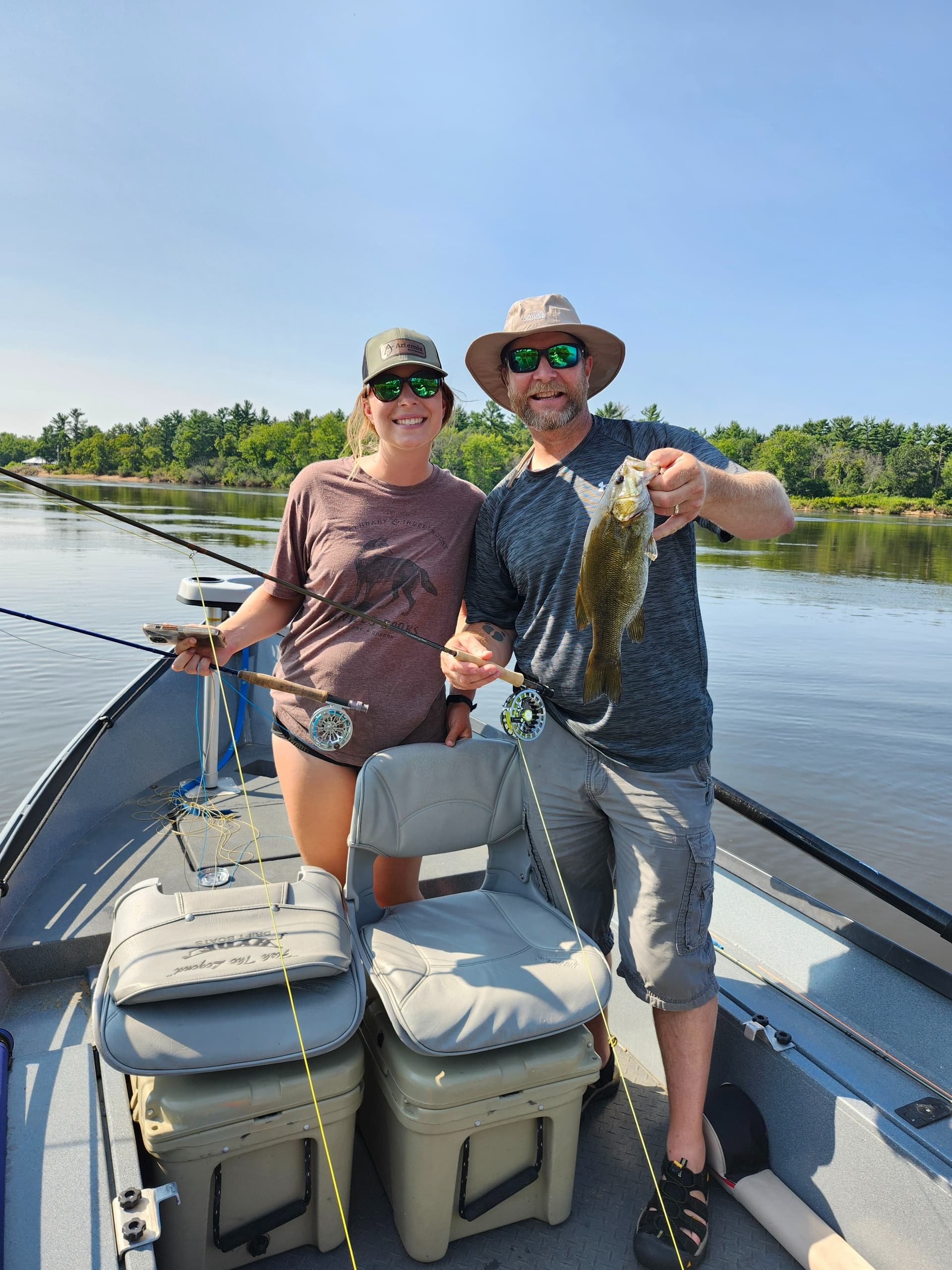 Anglers holding fresh catch aboard fishing boat on calm lake