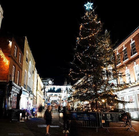 Nighttime town square with lit Christmas tree and shoppers