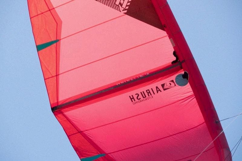 Close-up vibrant pink kite sail set against bright blue sky