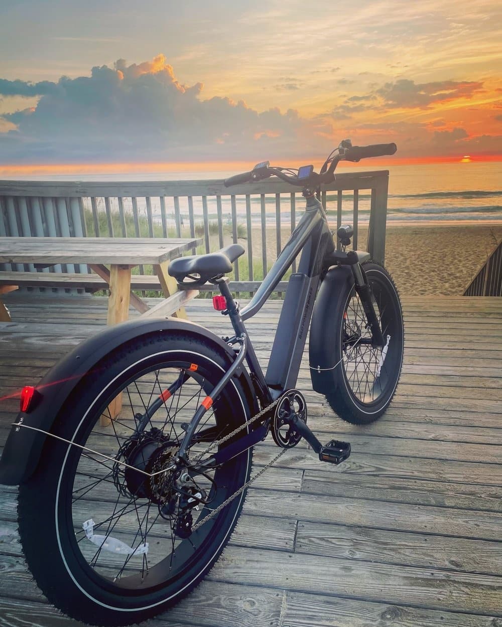 Fat-tire electric cruiser on beachfront boardwalk at sunset