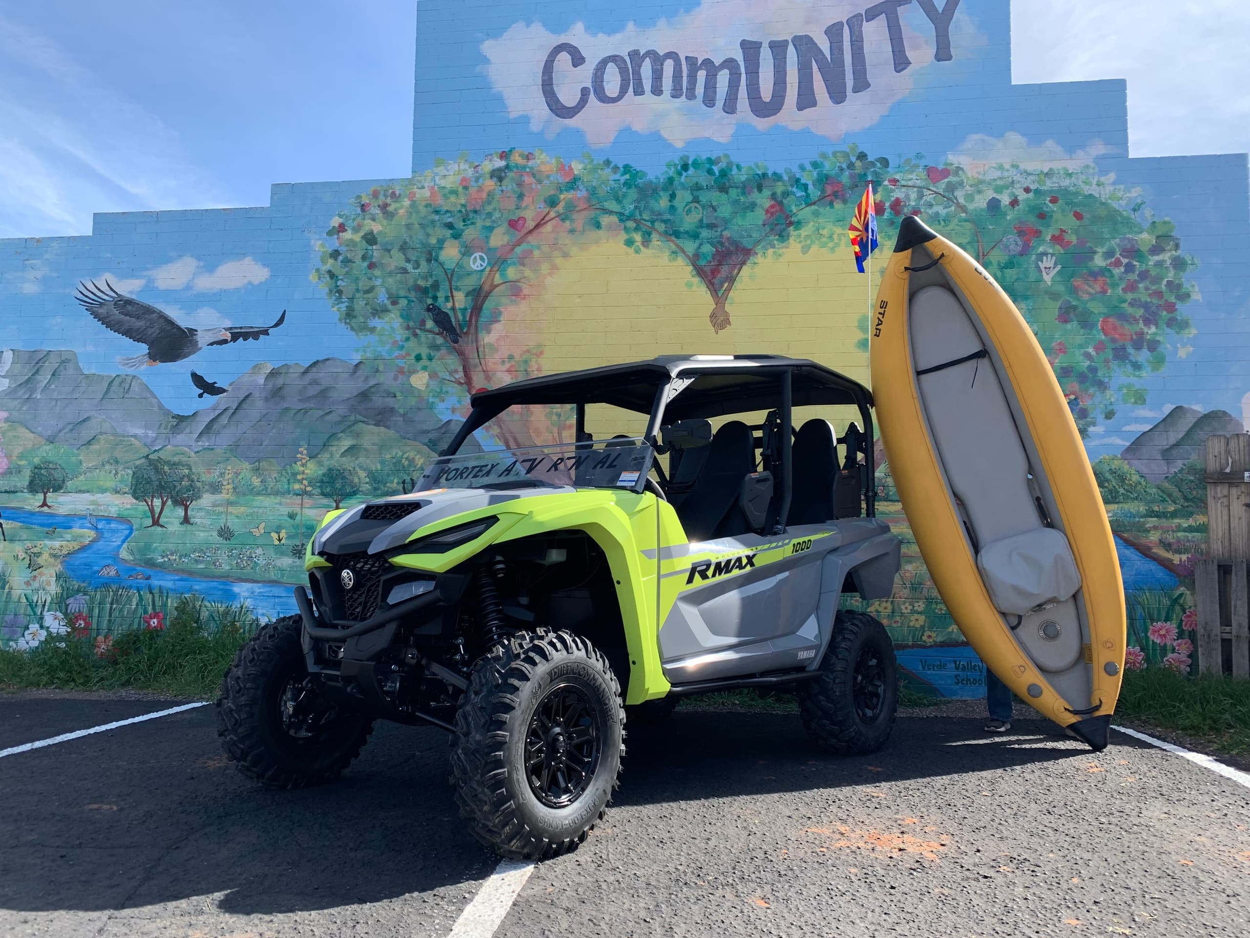 Bright yellow-green side-by-side UTV by community mural and kayak