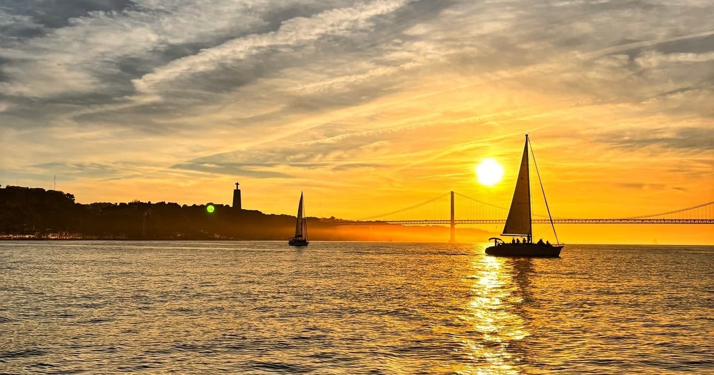 Sailboat silhouetted at sunset on Tagus River, Lisbon