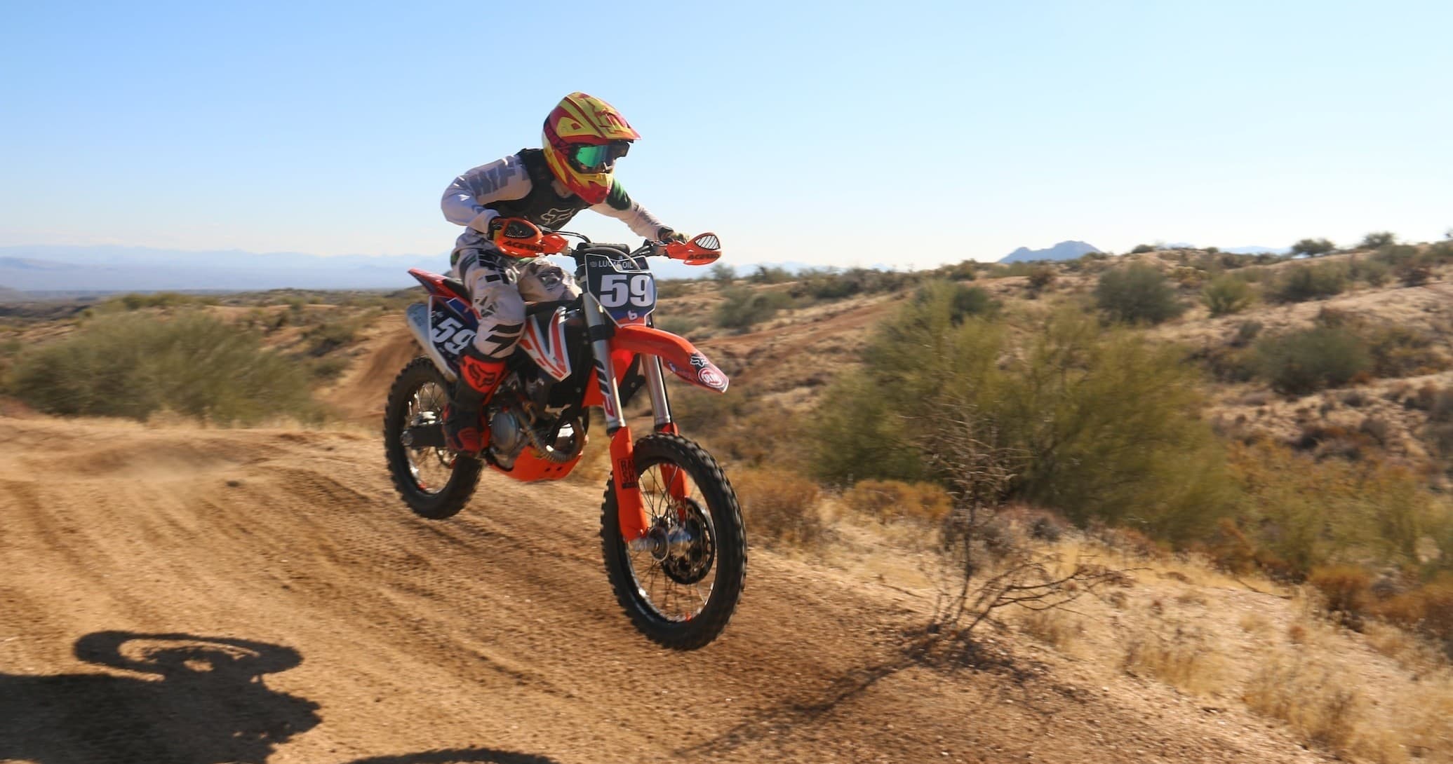 Dirt biker jumping over desert trail at sunset off-road ride