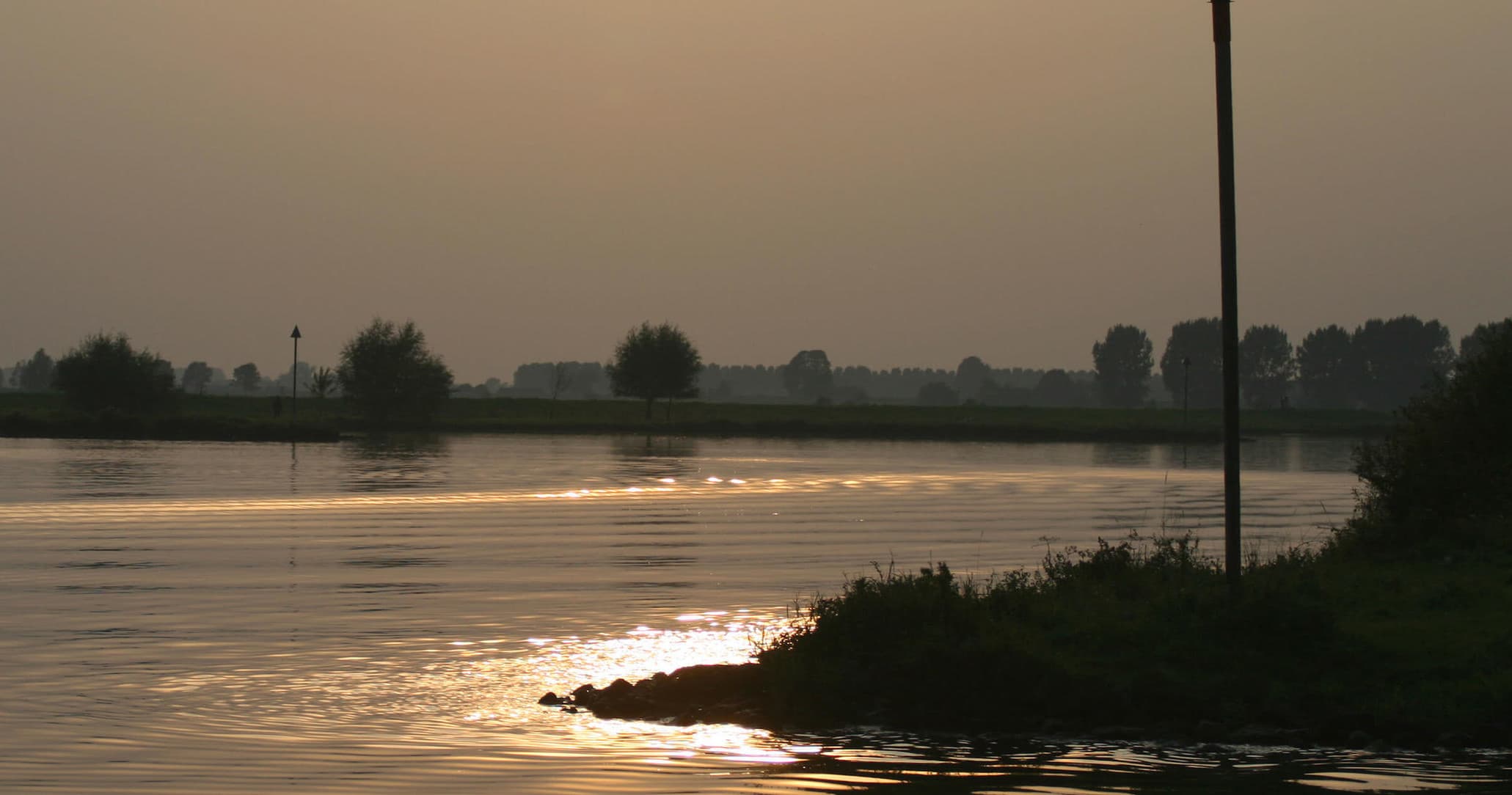 Sunset panorama on river with warm sky over Dutch landscape