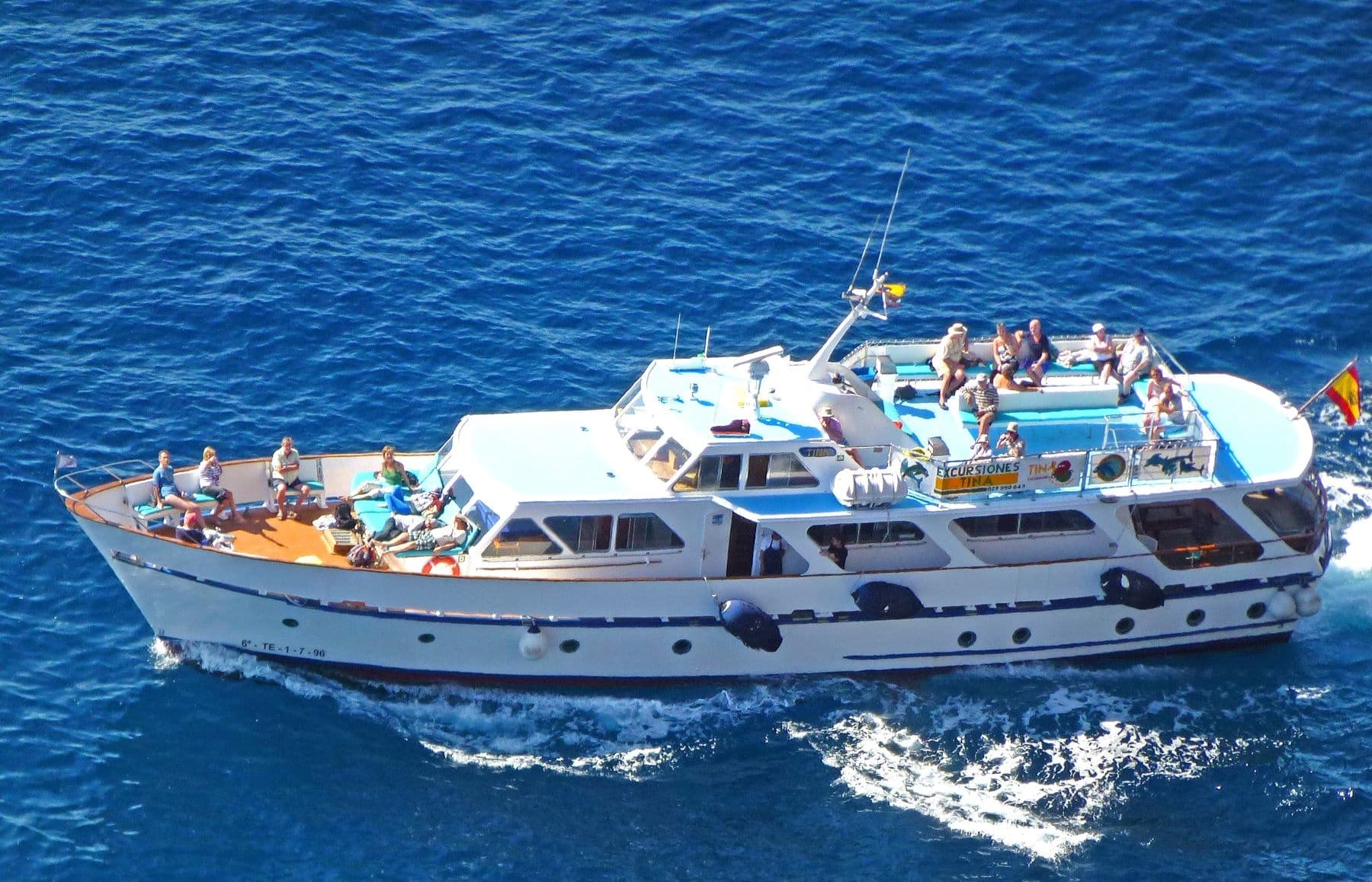 Large sightseeing yacht with passengers cruising bright blue sea