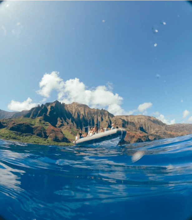 Split-view boat on ocean with underwater shot and cliffs