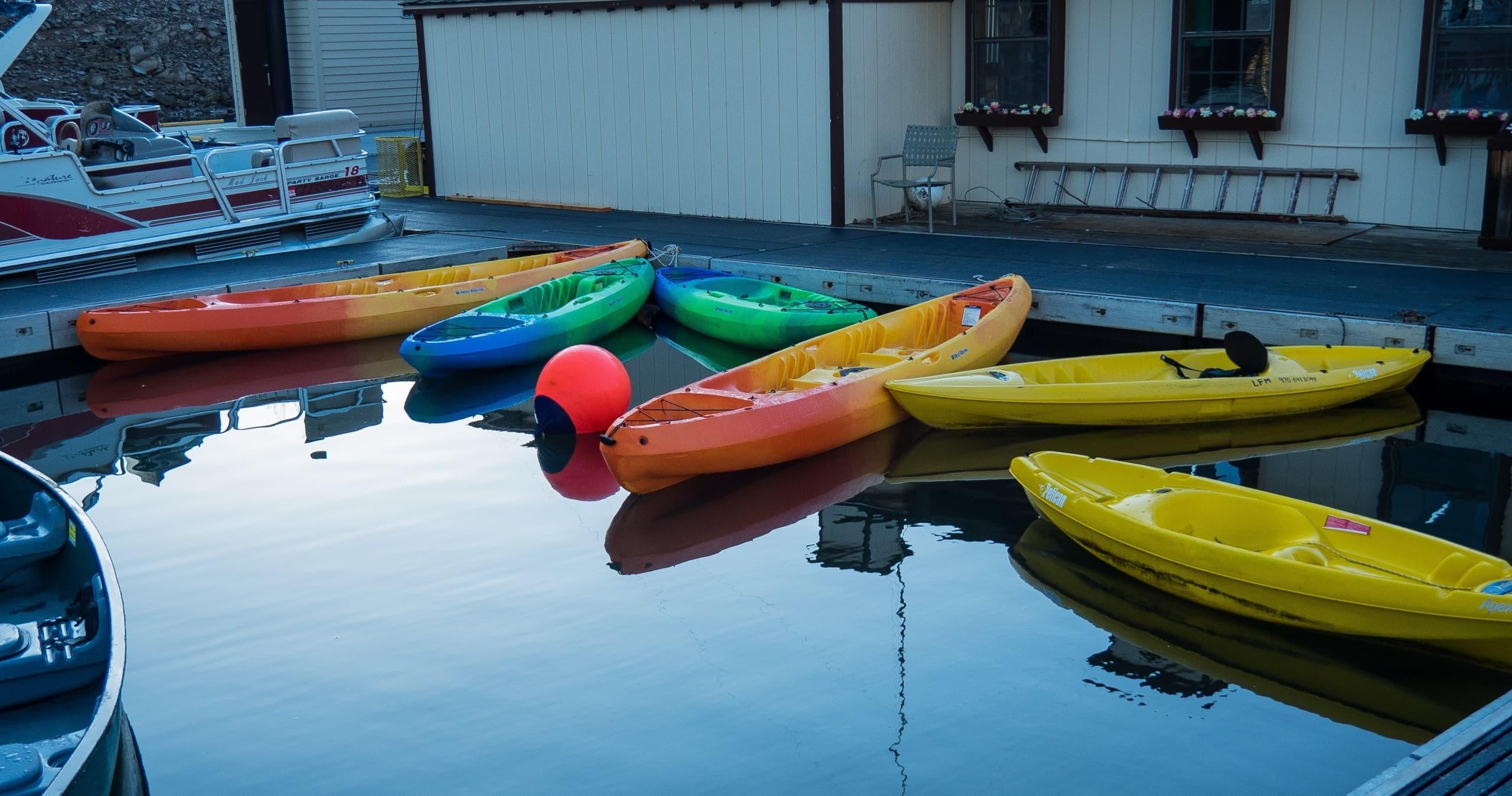 Colorful kayaks docked and reflected on a calm marina