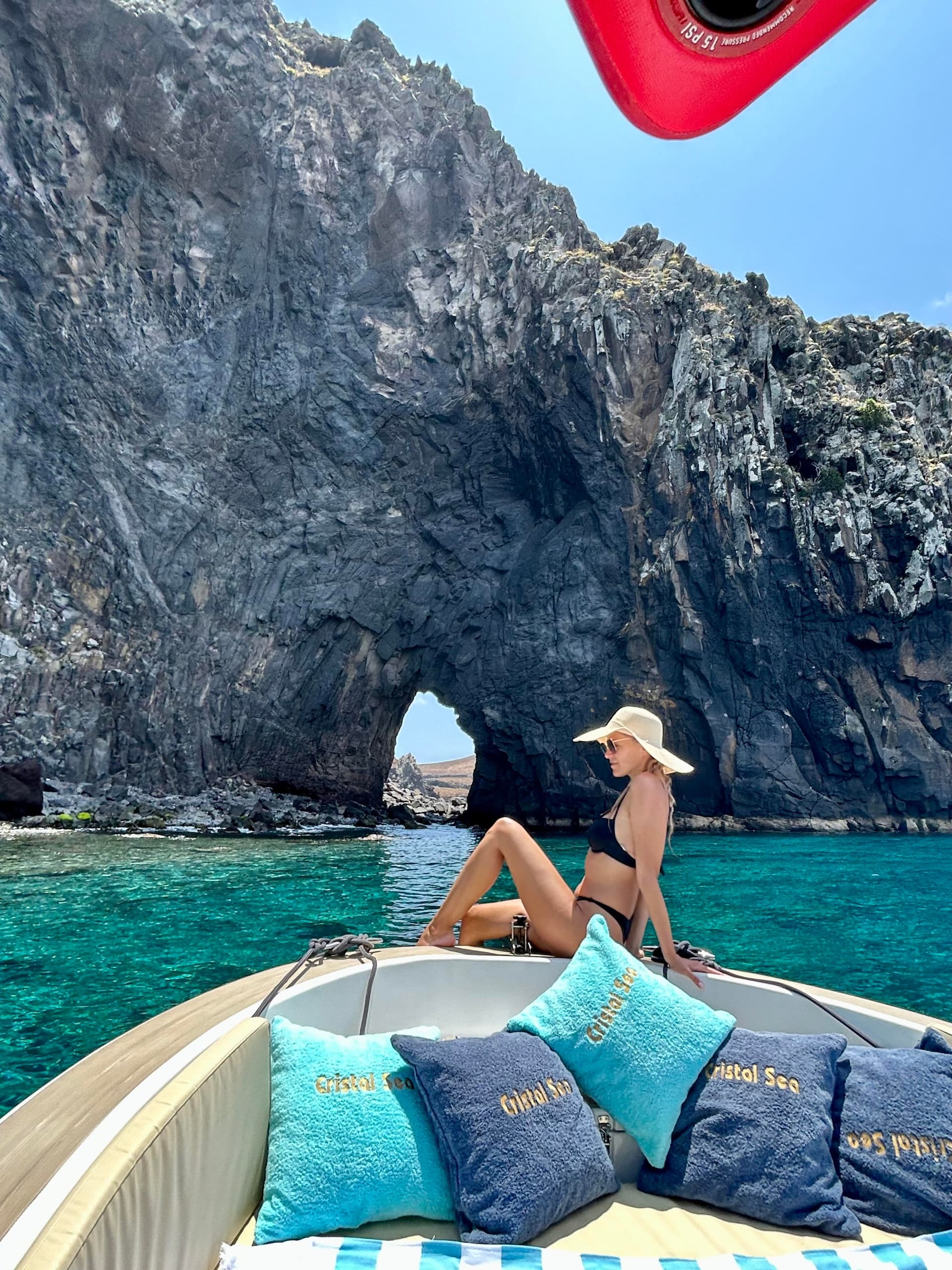 Woman lounging on boat by sea arch at coastal Madeira
