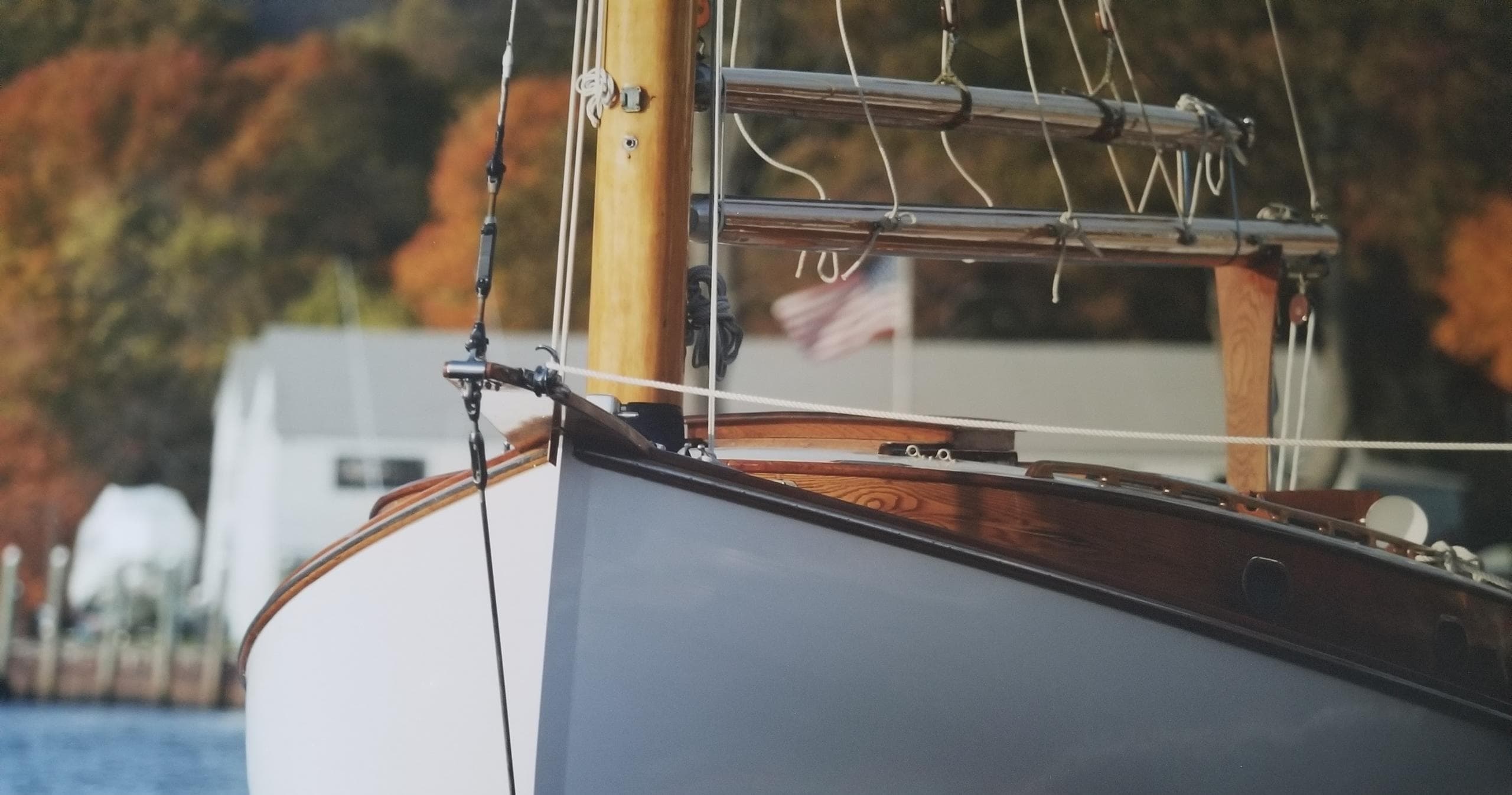 Close-up sailboat bow with autumn marina backdrop, peaceful sailing