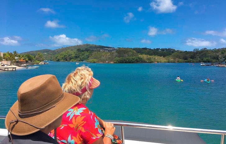Couple enjoying scenic Noosa River cruise from shaded boat deck