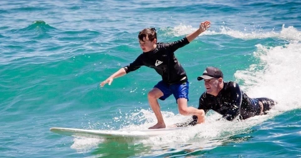 Instructor-taught surfing lesson riding blue ocean waves in Ensenada