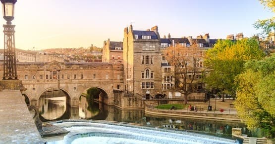 Historic riverside walk with bridge and city skyline, Bath