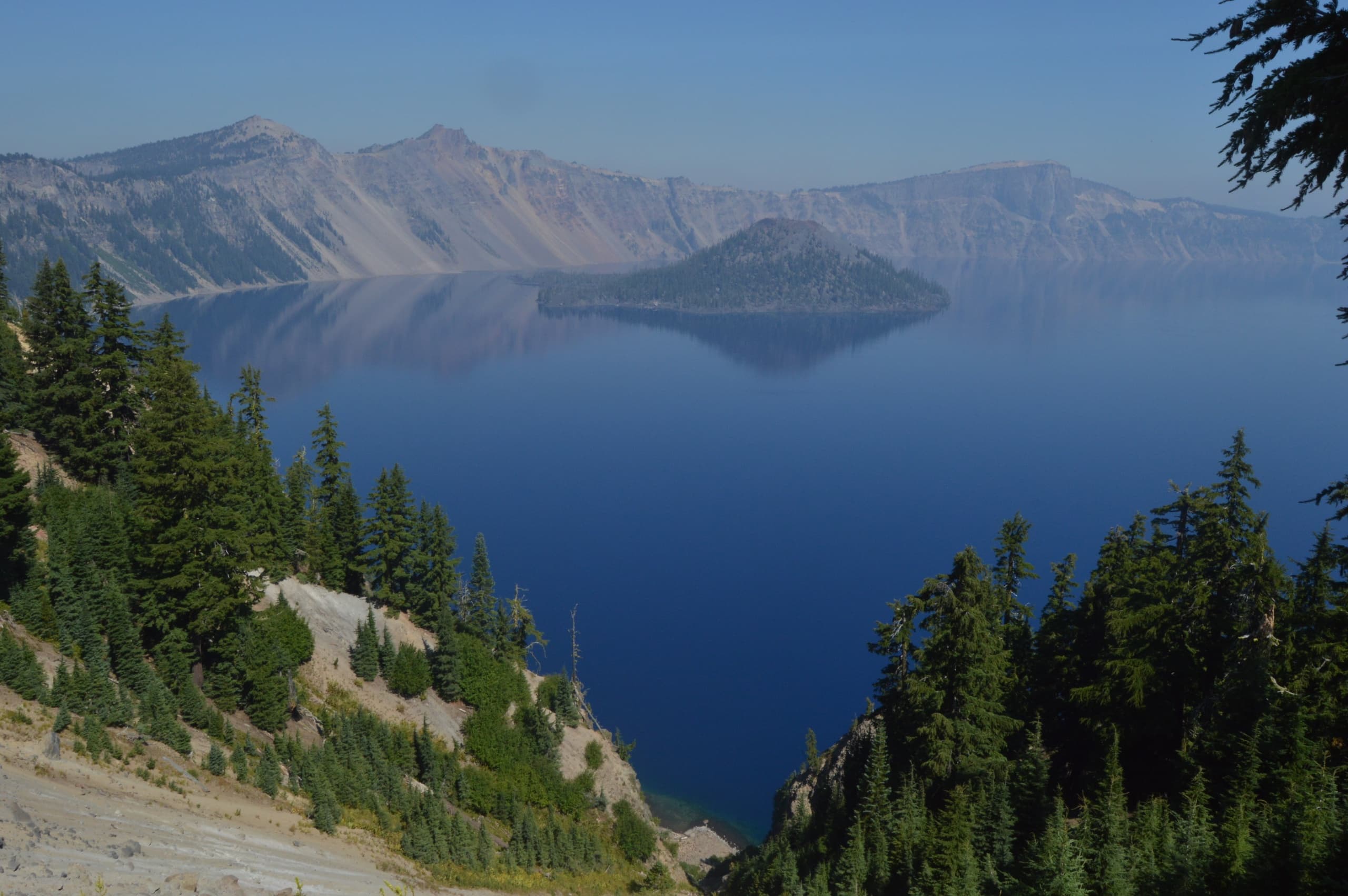 Hiking view of a crystal blue caldera lake and forested rim