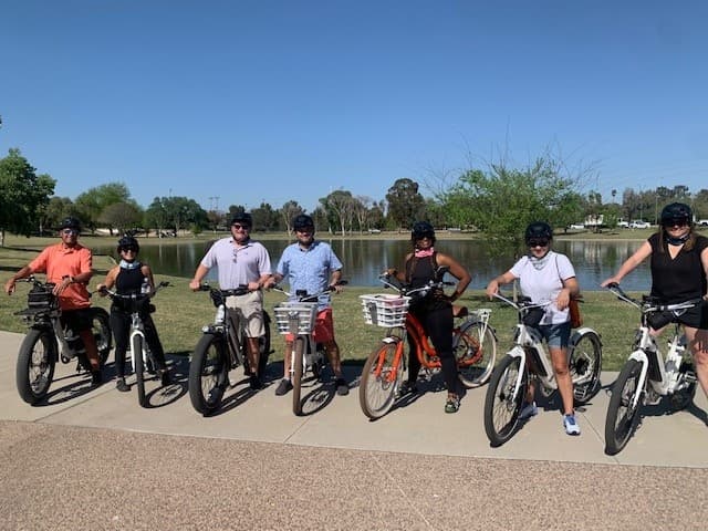 Guided e-bike tour group by lakeside path under blue sky in Arizona