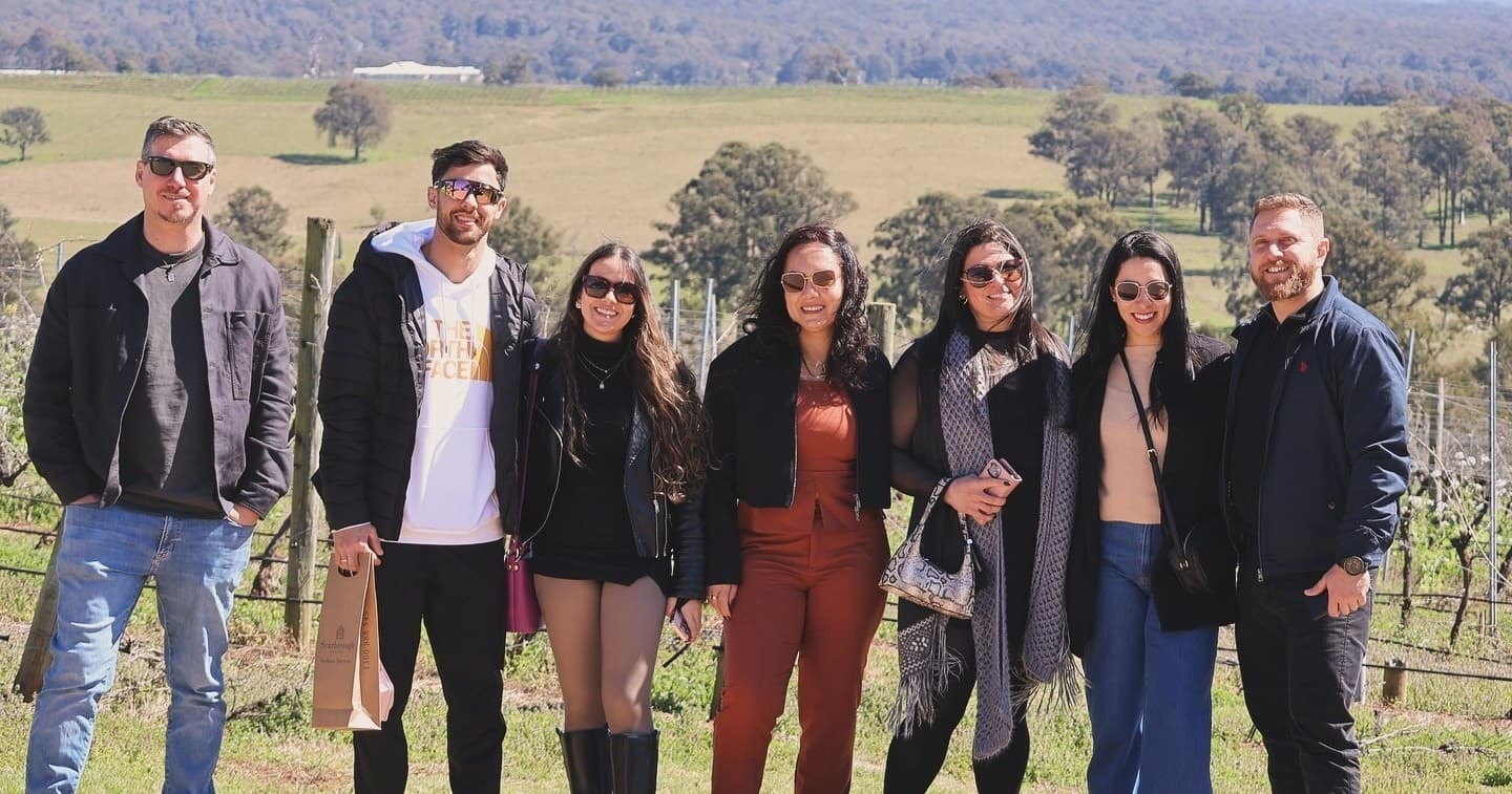 Group winery tour walking vineyard rows in open countryside