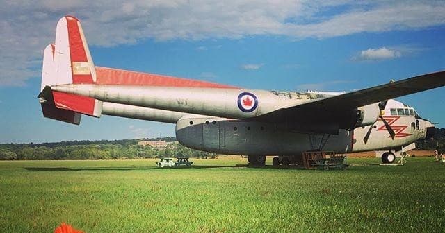 Restored heritage transport plane parked on sunlit grass airfield