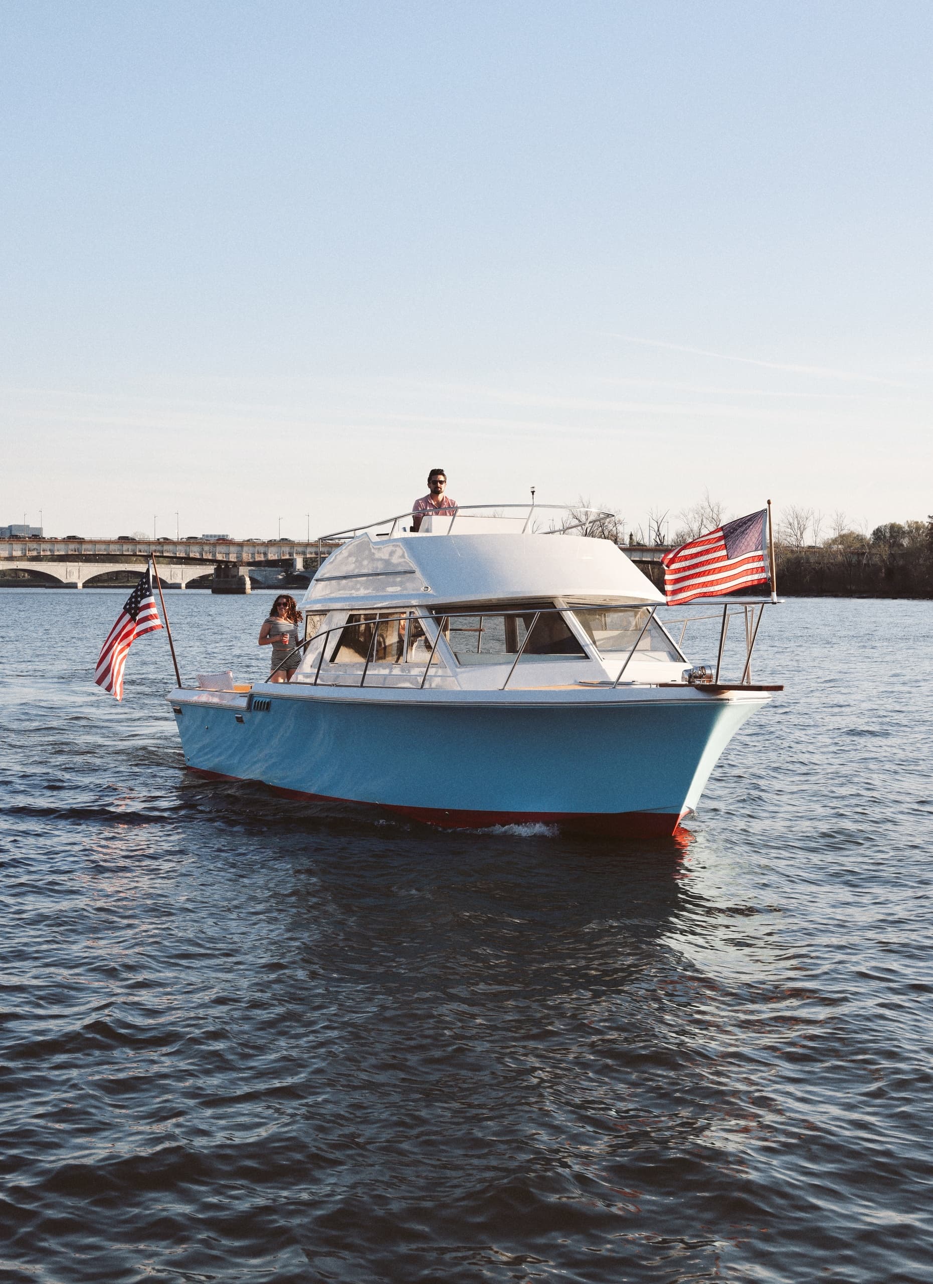 Small pleasure boat cruising on river with American flags