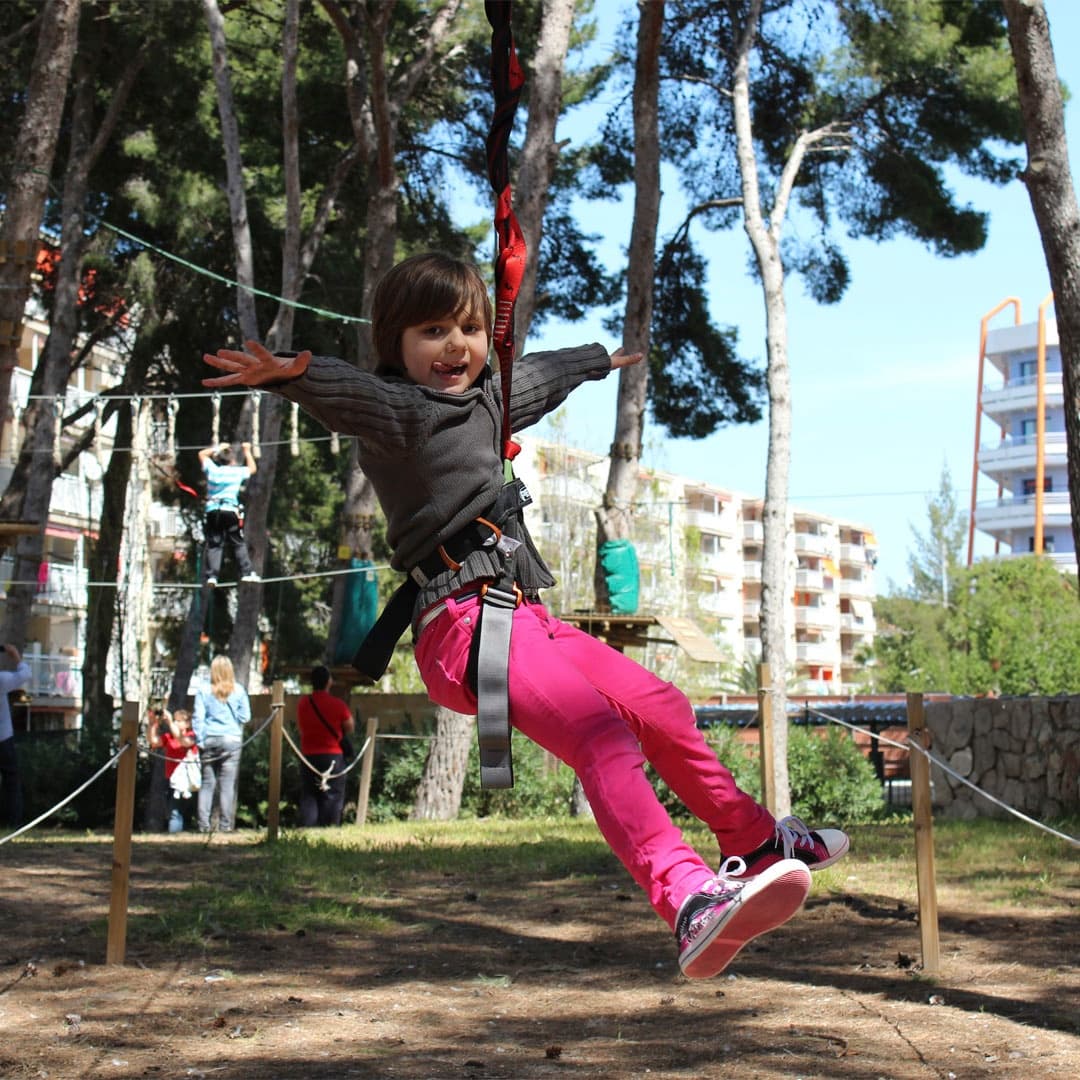 Child harnessed on zipline across pine park, mid-air thrill