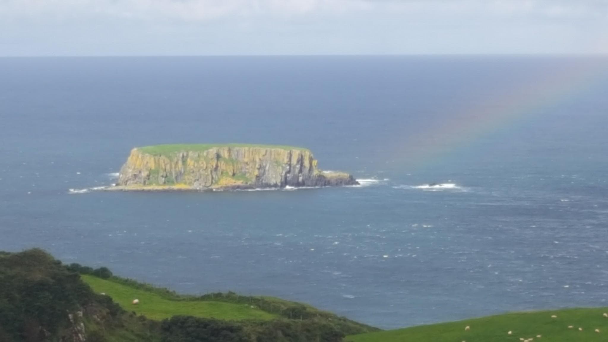 Seabird island and rainbow off Antrim coast scenic viewpoint