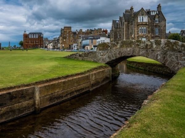 Historic stone bridge over stream beside coastal Scottish town