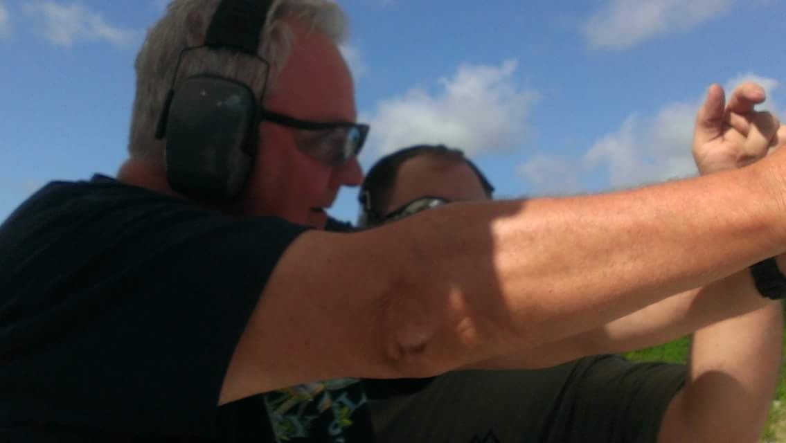 Instructor guiding adult shooter at sunny outdoor range