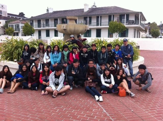 Large school group assembled at coastal plaza near historic Monterey hotel