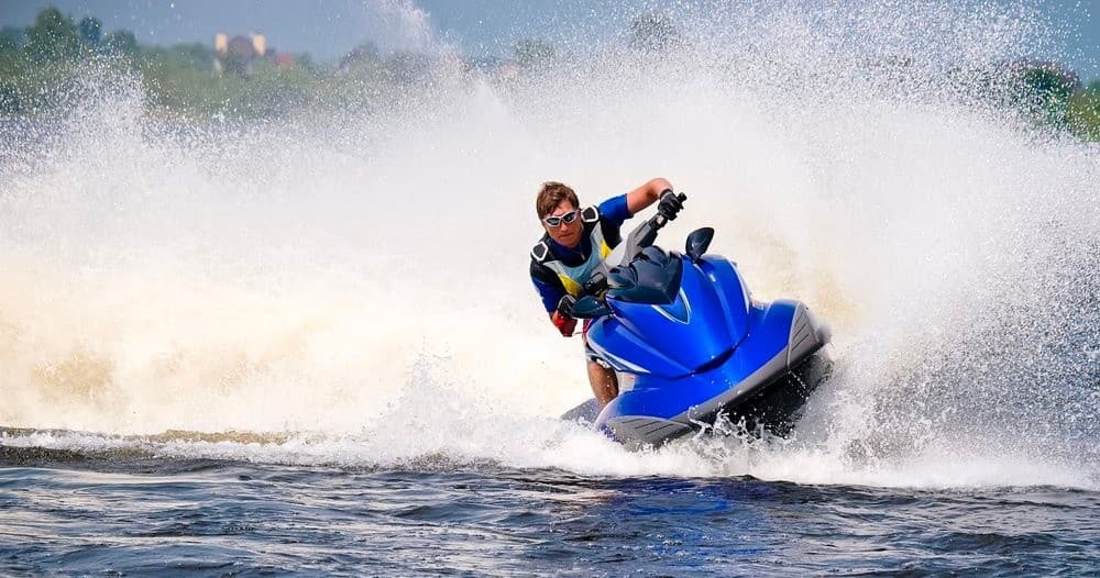 Jet ski rider carving through open lake water, high-speed splash