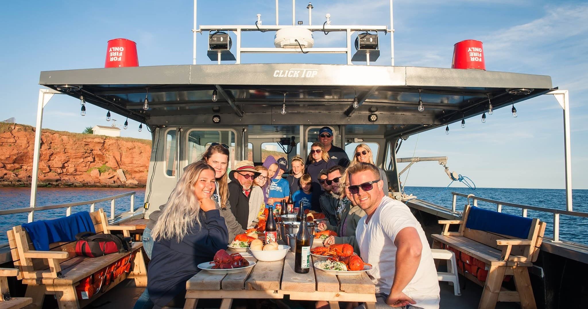 Fishermen and guests dining on charter boat near coastal cliffs