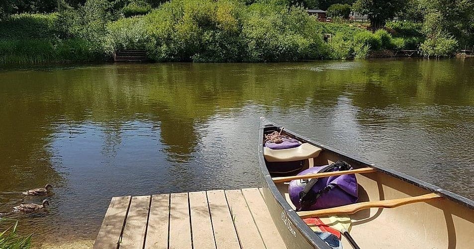 Empty canoe at wooden jetty on River Severn, serene launch