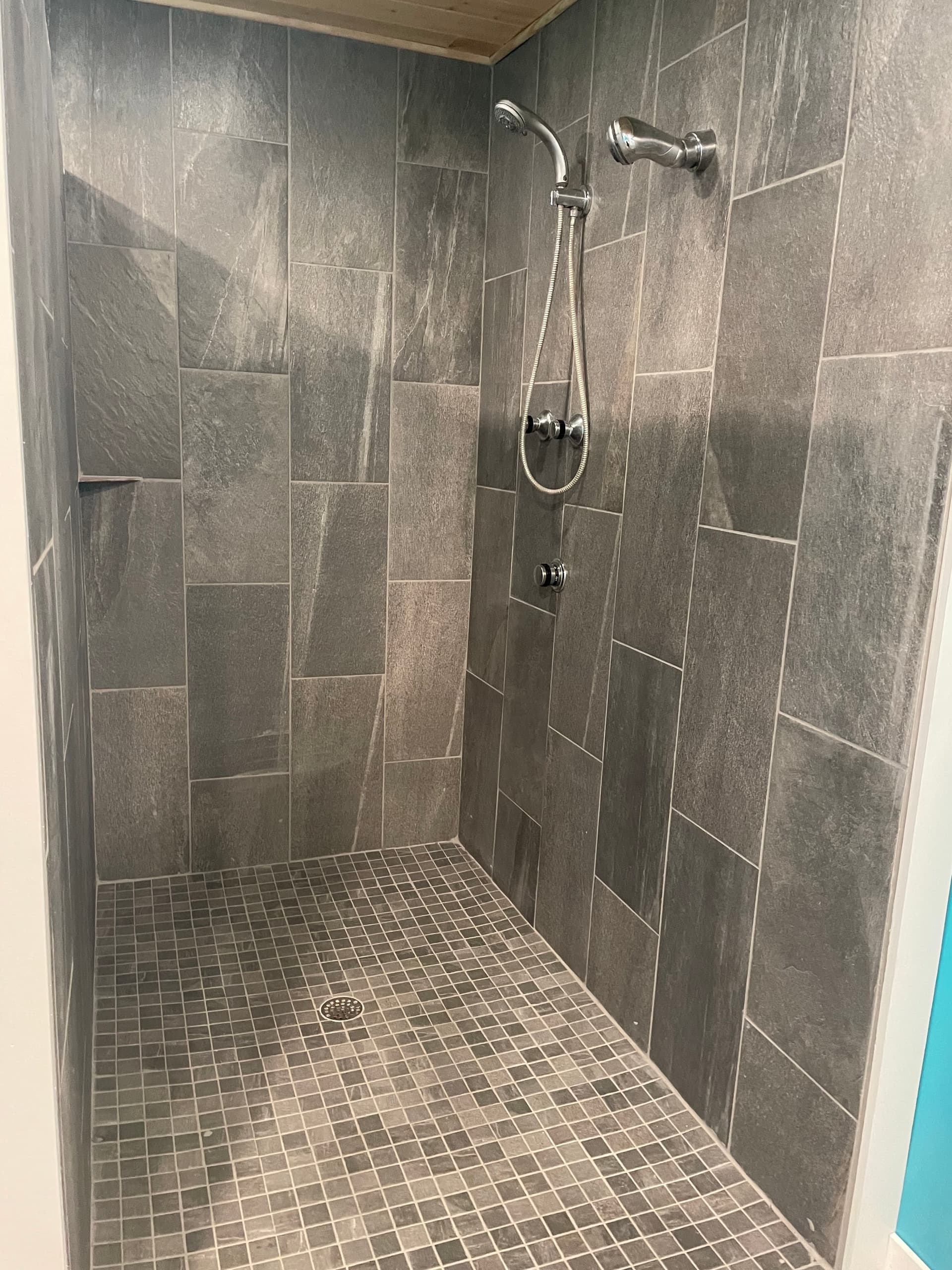 Tiled walk-in shower with dark stone tiles in cottage bath