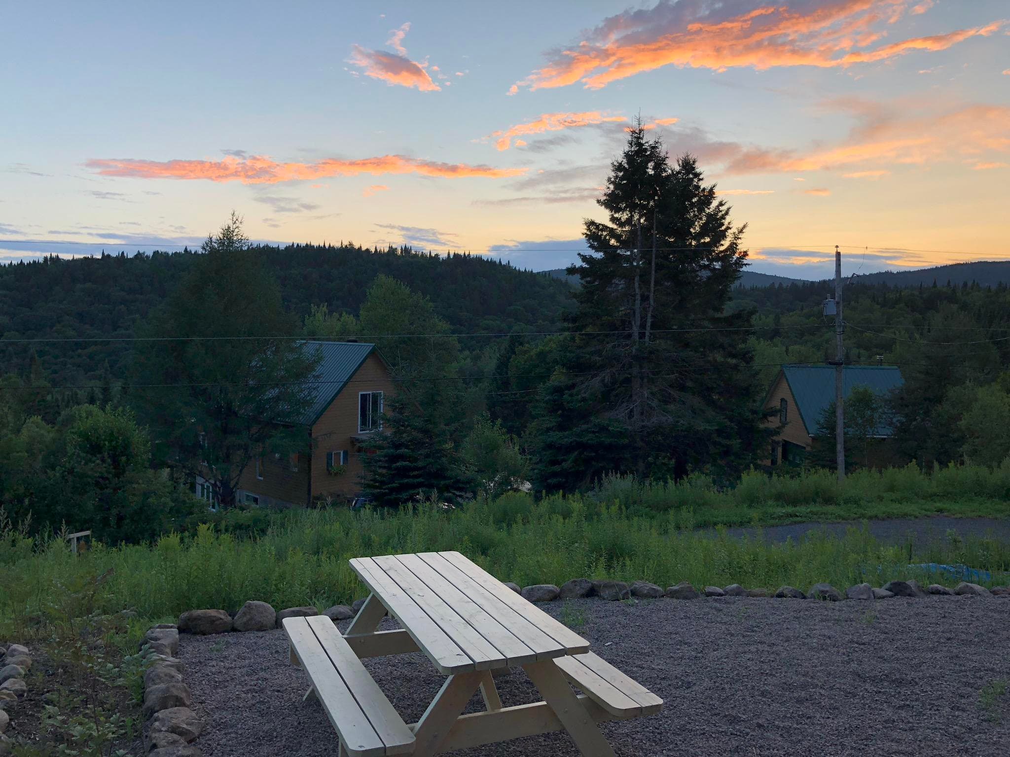 Sunset over valley with picnic table and distant cabin view