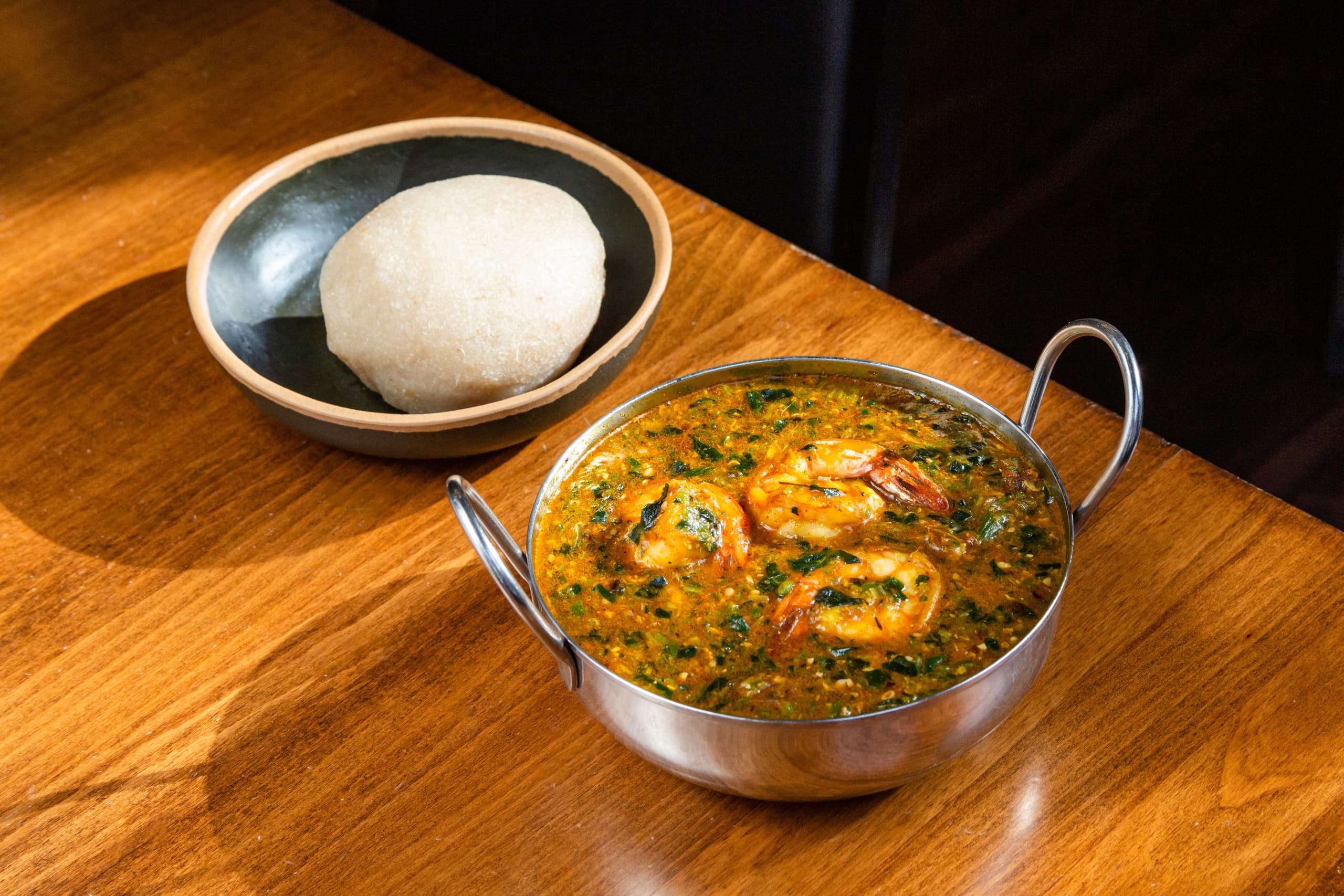 Hearty prawn curry in metal bowl on wooden table, rustic dining