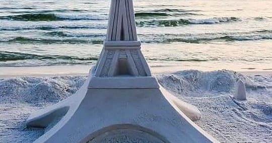 Intricate sandcastle Eiffel-style sculpture on ocean beach