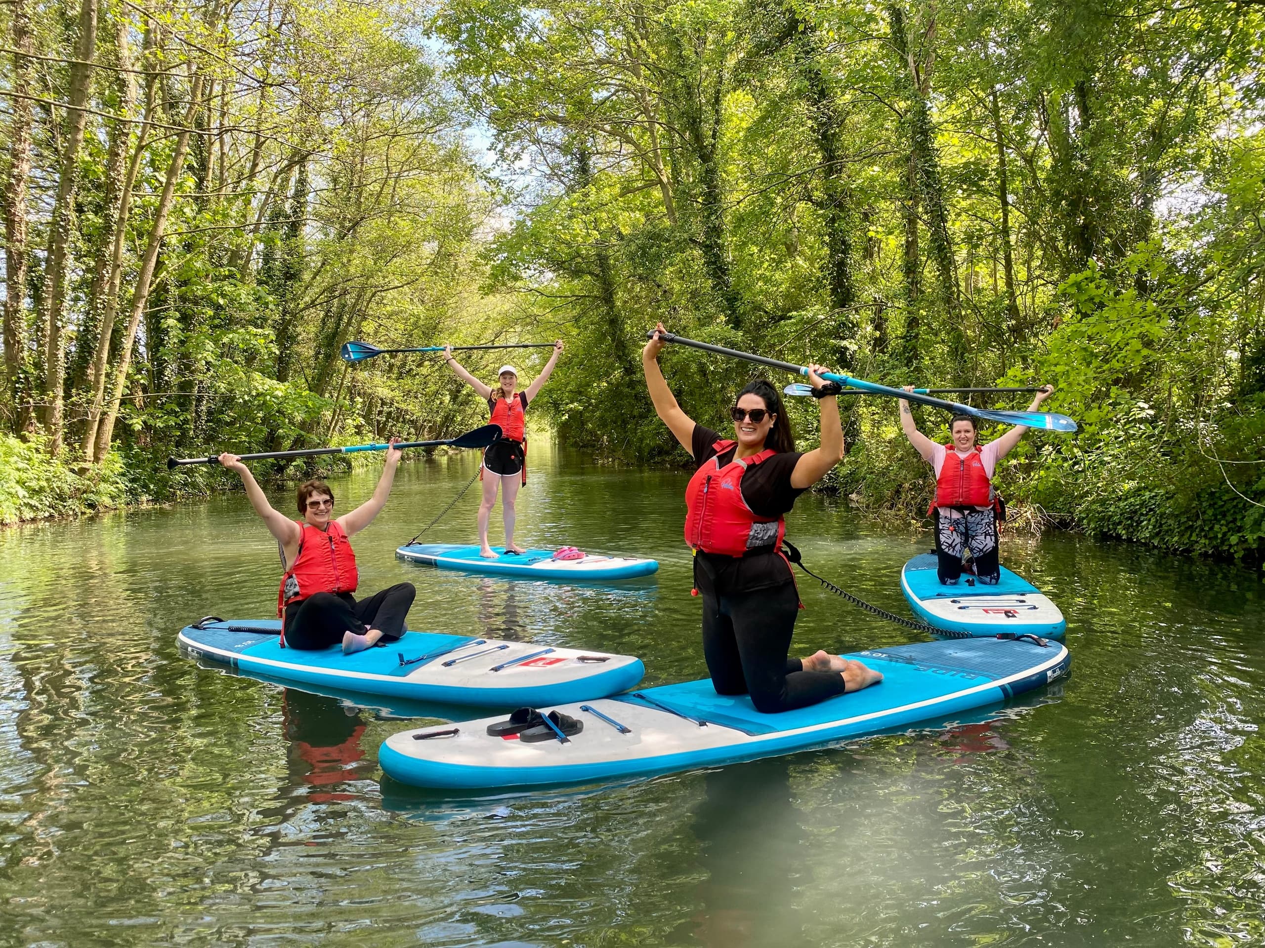 Stand-up paddleboarders celebrating on lush green river channel