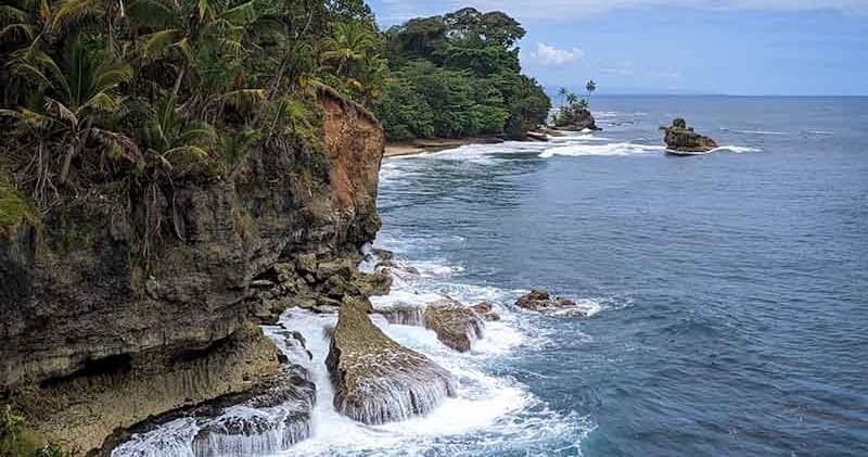 Cliffside coastal view with waves crashing on tropical shore