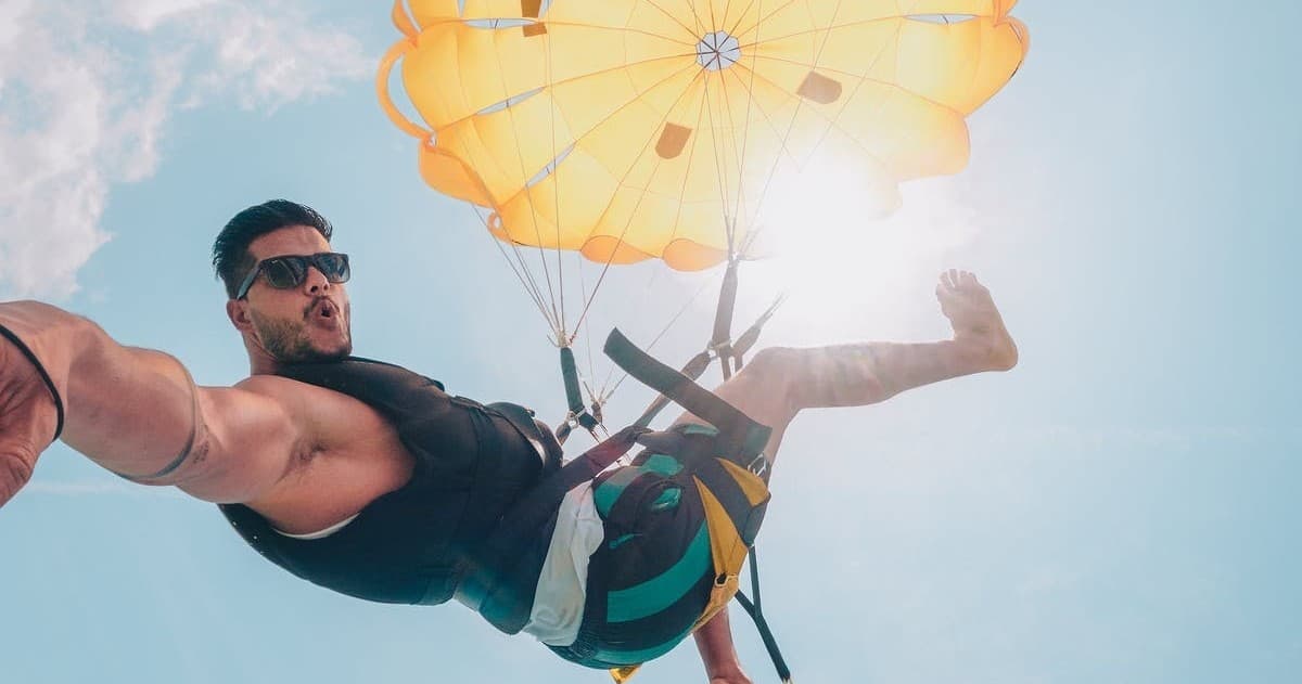Parasailer soaring above blue ocean with sunlit canopy