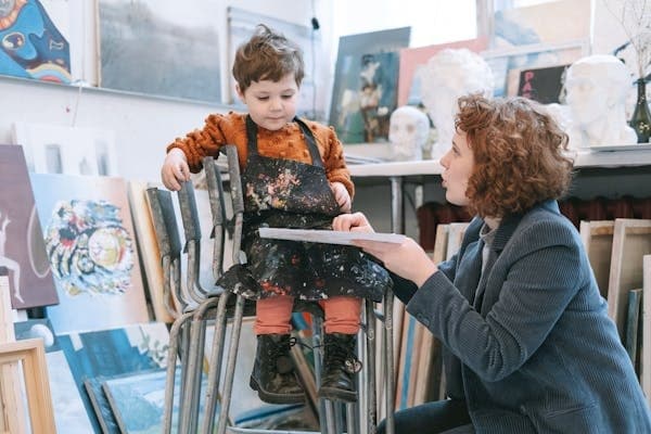 Art instructor guiding child in indoor painting studio session