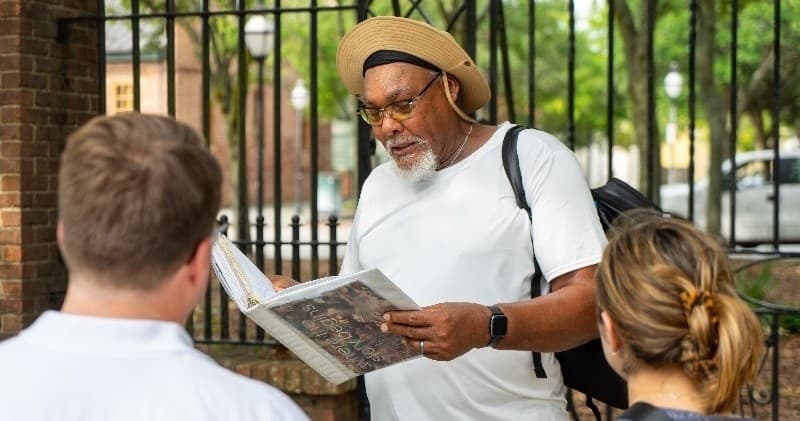Local guide reading map to small outdoor tour group near historic site