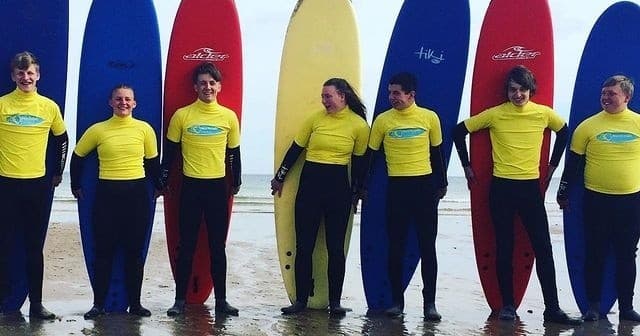 Surf instructors lined with colorful boards on sandy beach