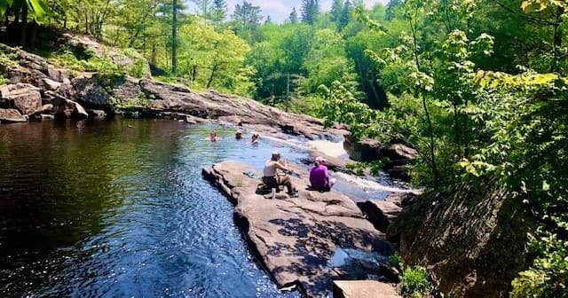 Scenic river gorge with rocky shore, hikers relaxing by water