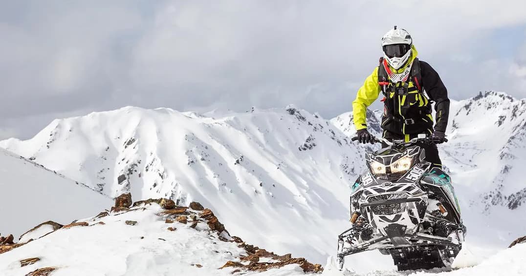 Rider snowmobiling on snowy alpine ridge in Revelstoke mountains