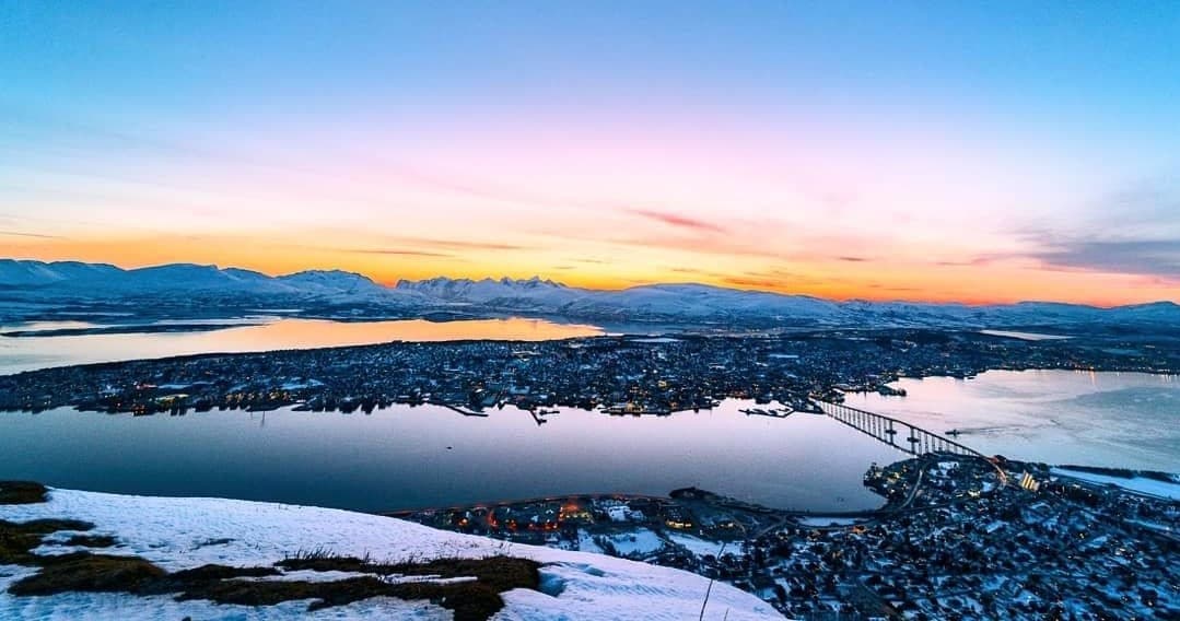 Colorful sunset over frozen fjord and coastal snowfields vista