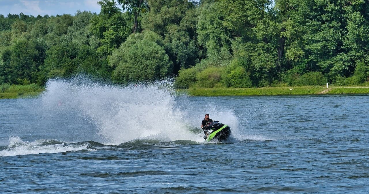 Jet ski racing on river with rider creating water spray