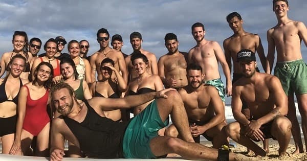 Large beach party group posing together on sunny shoreline