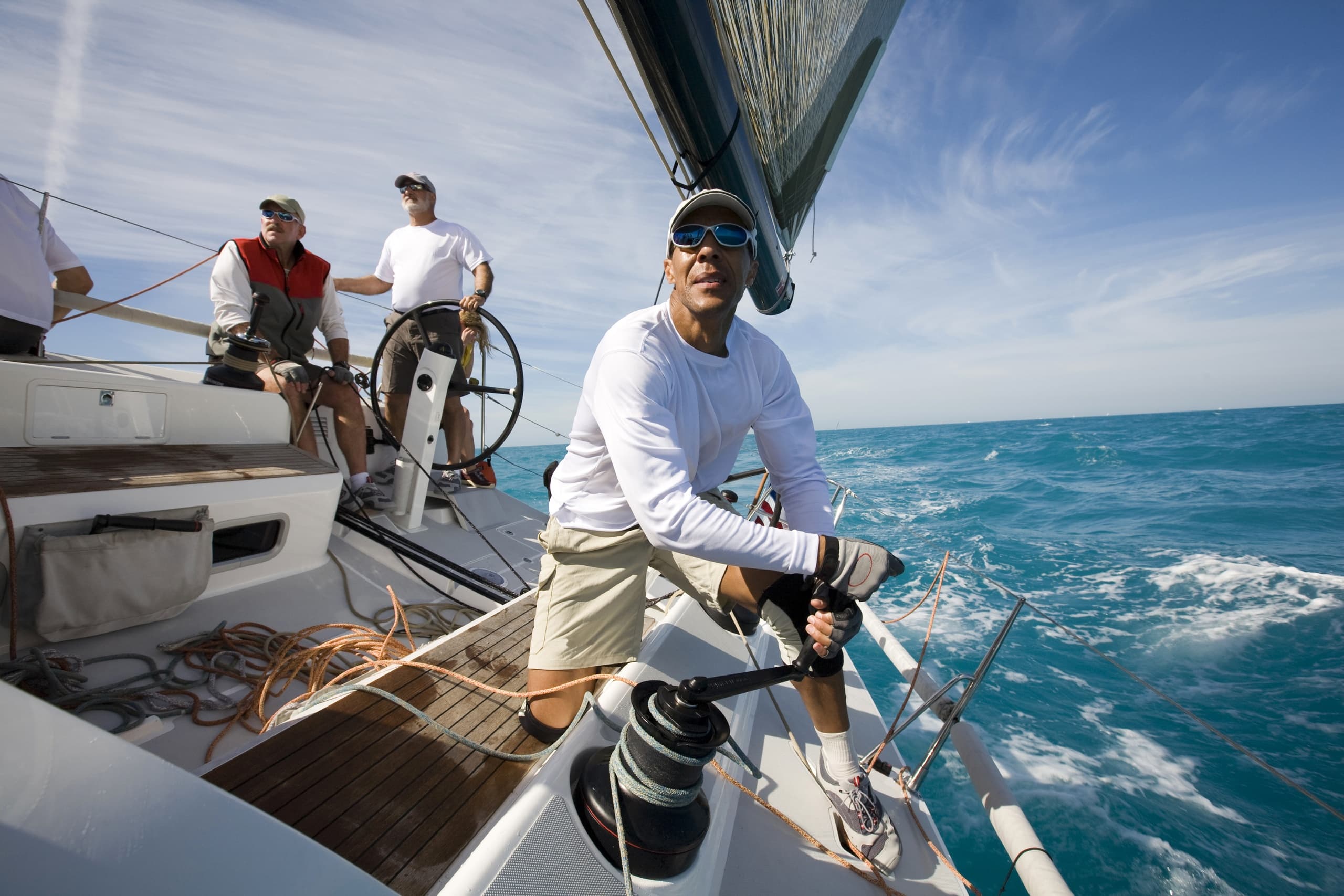 Skipper and crew trimming sails on ocean passage near coast