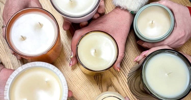 Hands holding candlemaking jars on wooden table in craft studio