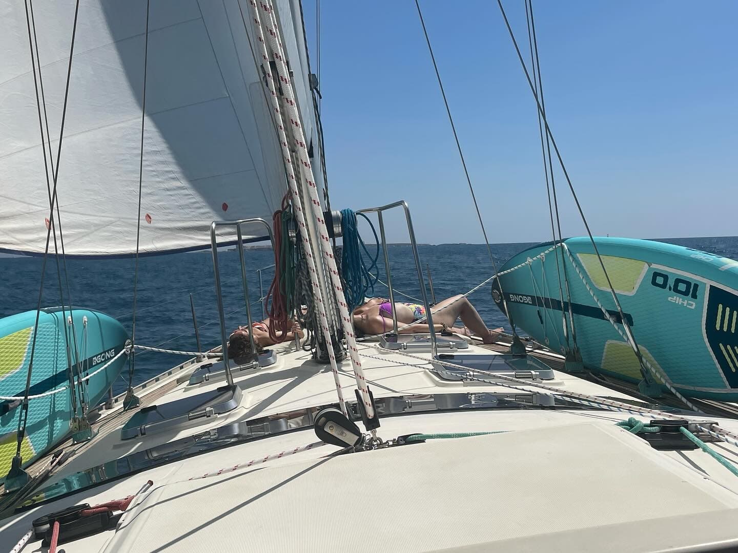 Forward deck view of sailing with sails and paddleboards underway