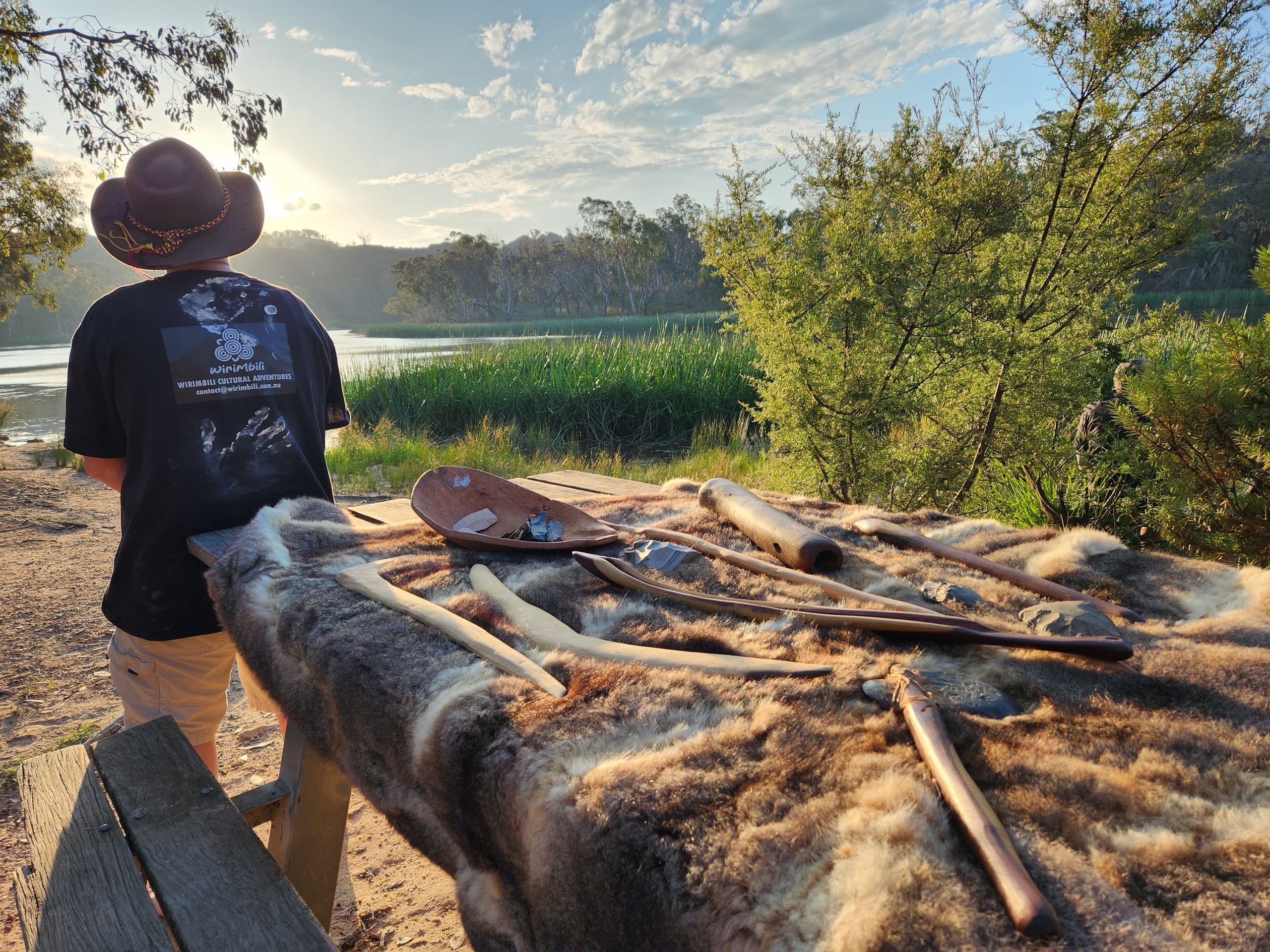 Sunrise riverbank scene with guide and traditional instruments on fur