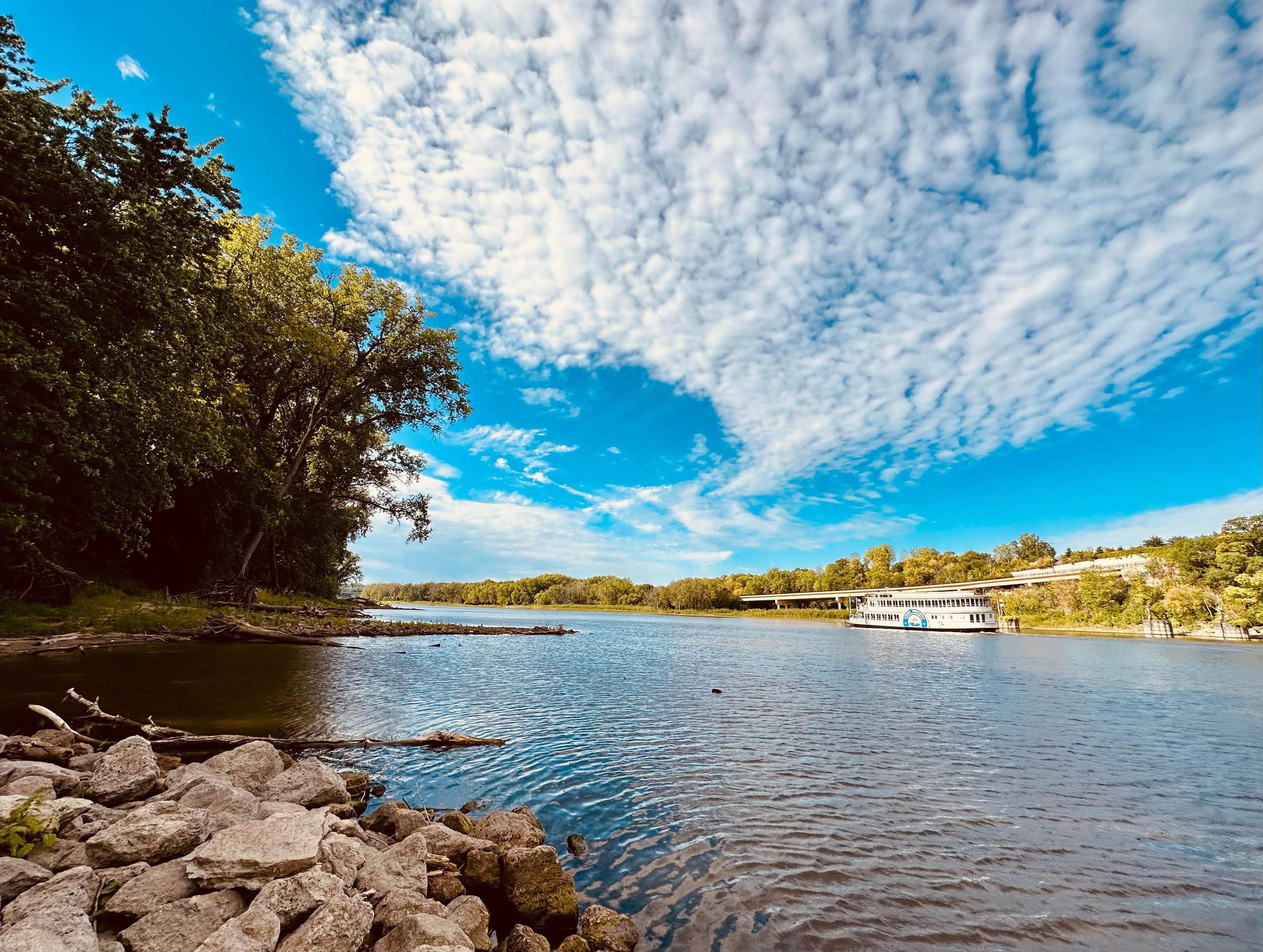 Scenic river panorama with boat and dramatic cloud-filled sky